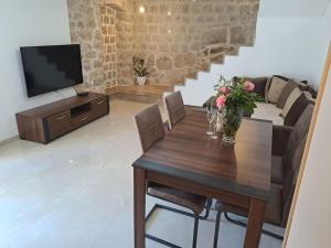 a living room with a wooden table and a television at Stara kamena kuca Lustica in Luštica