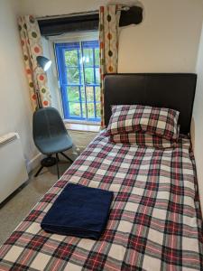 a bedroom with a bed and a chair and a window at Bwthyn Heddwch - Peace Cottage in Machynlleth