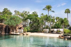 a resort pool with chairs and a beach with palm trees at JW Marriott Gold Coast Resort & Spa in Gold Coast