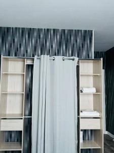 a bathroom with a shower curtain and shelves at DAMA Lodge in La Ferté-Bernard