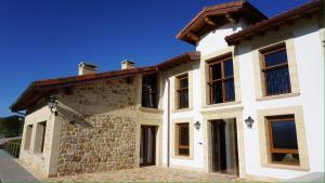 a large white house with a roof at Apartamentos Villa Sofía in San Vicente de la Barquera
