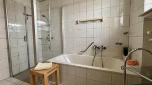 a white bathroom with a tub and a shower at Ferienwohnungen Hoefchen in Eckfeld +40 photos