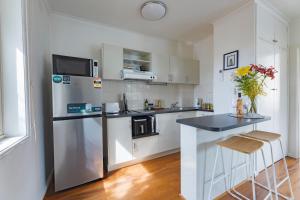 une cuisine avec des armoires blanches et un comptoir noir dans l'établissement St Kilda Studio Apartment walking distance to the beach, à Melbourne 7 autres photos