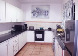 Una cocina con gabinetes blancos y encimeras negras. en Affordable Decent Private Room In a Shared Apartment with a Pool, en Sandton