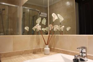 a white vase with white flowers in a bathroom at Apartamentos Casa Germana in Tapia de Casariego