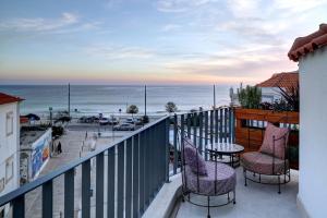 uma varanda com cadeiras e uma mesa e o oceano em Casa da Praça Guest House em Sesimbra