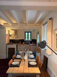 un lungo tavolo in legno con sedie e una cucina di Maison de charme près de Genève, vue et terrasse - idéal familles! a Étrembières