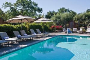 a swimming pool with lounge chairs and umbrellas next to a pool at Wine Country Inn & Cottages Napa Valley in Barro