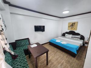 a bedroom with a bed and a chair and a table at MB's Garden Inn in Mactan