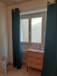 a bedroom with a dresser and a window with blue curtains at Maisonnette pour halte angevine in Les Ponts-de-Cé