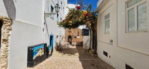 a narrow alley with flowers hanging from buildings at Casa Alzira By ALzira in Albufeira