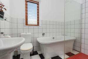 a bathroom with a toilet and a tub and a sink at At South Boutique Guesthouse in Cape Town +19 photos