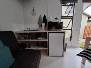 a kitchen with a microwave and a refrigerator in a living room at Petite Cottage Plett in Plettenberg Bay