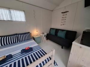 a small bedroom with a bed and a couch at Petite Cottage Plett in Plettenberg Bay