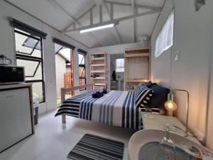 a bedroom with a bed and a sink in a room at Petite Cottage Plett in Plettenberg Bay