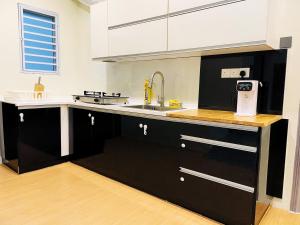 a kitchen with black cabinets and a sink at Allbes Klang Room in Klang