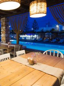 a wooden table in a restaurant with a pool at Parosland Hotel in Aliki