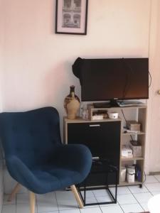 ein Wohnzimmer mit einem blauen Sessel und einem Fernseher in der Unterkunft Appartement F2 Paris la villette 4 chemins in Aubervilliers