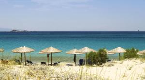 a group of umbrellas on a beach with the ocean at Ploes Seaside Houses in Plaka