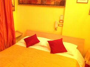 una camera da letto con un letto con due cuscini rossi sopra di Bed & Breakfast Federico II a Foggia