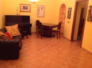uma sala de estar com um piano, uma mesa e cadeiras em Bed & Breakfast Federico II em Foggia
