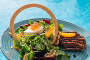 a plate of food with a salad and meat at Parosland Hotel in Aliki
