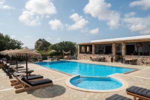 a swimming pool with lounge chairs and a resort at Parosland Hotel in Aliki