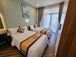 a hotel room with two beds and a window at Khách sạn Miami Ninh Thuận in Phan Rang–Tháp Chàm