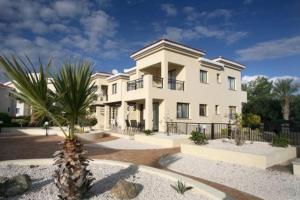 Una gran casa blanca con una palmera delante de ella. en Faros Beach, en Pafos
