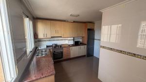 a kitchen with wooden cabinets and a sink at Casa Frijol 20metres from the beach in Los Alcázares