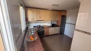 a small kitchen with wooden cabinets and a sink at Casa Frijol 20metres from the beach in Los Alcázares