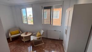 a room with a chair and a table and two windows at Casa Frijol 20metres from the beach in Los Alcázares