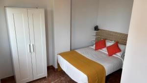 a bedroom with a bed with two red pillows at Casa Frijol 20metres from the beach in Los Alcázares