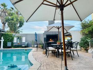 a patio with a table and umbrella next to a pool at Welgemoed Villa in Bellville