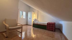 a small bedroom with a bed and a chair at Casa Frijol 20metres from the beach in Los Alcázares