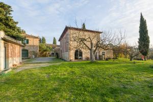 una antigua casa de piedra con un patio verde en Agriturismo Santa Croce en San Gimignano