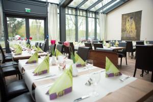 a dining room with tables and chairs and windows at Gästehaus Südheide in Hambühren