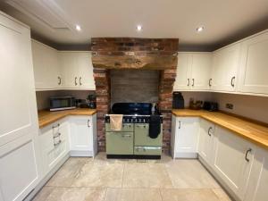 a kitchen with white cabinets and a green oven at Fitzherbert Cottage in Swynnerton