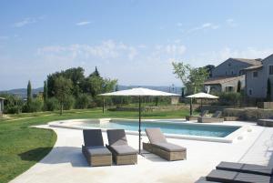 uma piscina com duas cadeiras e um guarda-sol em Résidence Les Petitons em Oppède