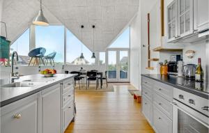a kitchen with white cabinets and a large window at Three-Bedroom Holiday Home In Blokhus in Blokhus