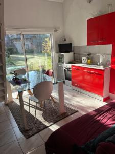 a kitchen with a glass table and red cabinets at La Faisanderie in Saint-Florent-sur-Cher