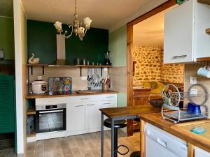 a kitchen with green walls and white cabinets and a table at Gîte La Cahute in Bourganeuf