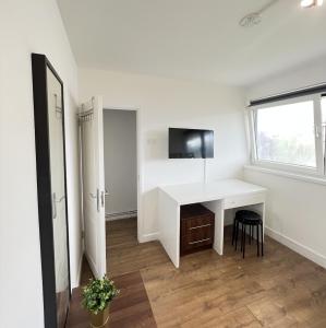 Habitación con escritorio blanco y ventana. en London Rooms King's Cross, en Londres