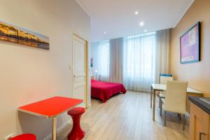 Habitación pequeña con mesa roja y dormitorio. en Les Studios De La Place (Part-Dieu), en Lyon