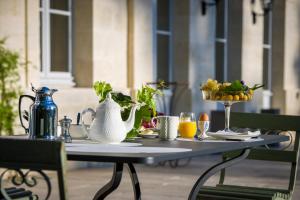 a table with a tea kettle and a bowl of fruit at Château Le Pape B&B in Léognan