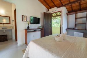 a bedroom with a bed and a sink and a television at Pousada Samambaia in Trancoso