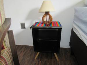 a lamp sitting on a night stand next to a bed at Quarto Suíte Amora in Atibaia