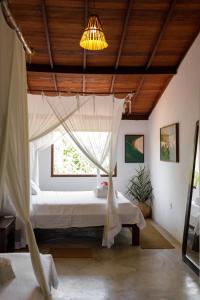 a bedroom with a bed with a mosquito net at Vila Fruta Pão in Caraíva