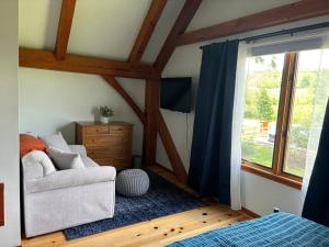 a bedroom with a bed and a chair and a window at Waneta Way Cottage in Hammondsport