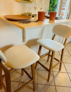a kitchen with two white chairs and a counter with wine glasses at La Toulousaine  +11 photos